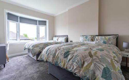 a bedroom with two beds and a window at 4 Bedrooms Homely House - Sleeps 6 Comfortably with 6 Double Beds,Glasgow, Free Street Parking, Business Travellers, Contractors, & Holiday-Goers, Near All Major Transport Links in Glasgow & City Centre, Perfect for Common Wealth Games 2026 in Glasgow