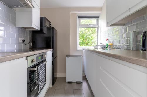 a kitchen with white counters and a white refrigerator at 4 Bedrooms Homely House - Sleeps 6 Comfortably with 6 Double Beds,Glasgow, Free Street Parking, Business Travellers, Contractors, & Holiday-Goers, Near All Major Transport Links in Glasgow & City Centre, Perfect for Common Wealth Games 2026 in Glasgow