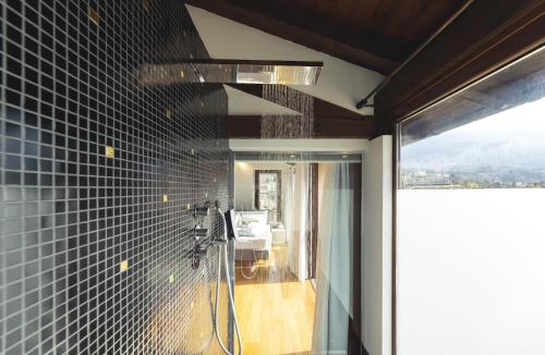La salle de bains est pourvue d'une douche avec du carrelage noir sur le mur. dans l'établissement Hi room vicolo del vò, à Trente