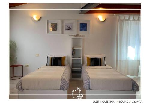 two beds in a room with white walls at Guest House Pina in Rovinj