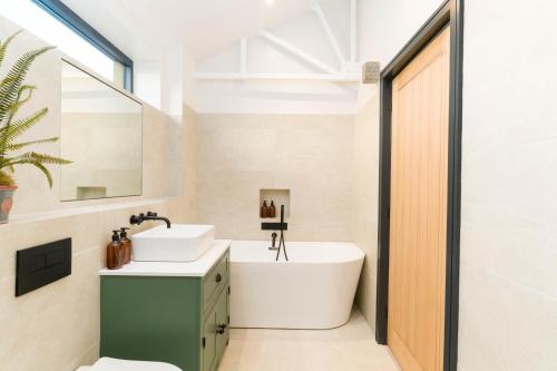 y baño con bañera blanca y lavamanos. en Appletree - a newly converted luxury barn in Warwickshire on our farm, en Evesham