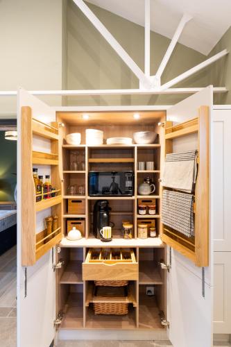 a kitchen with white cabinets and wooden shelves at Appletree - a newly converted luxury barn in Warwickshire on our farm in Evesham