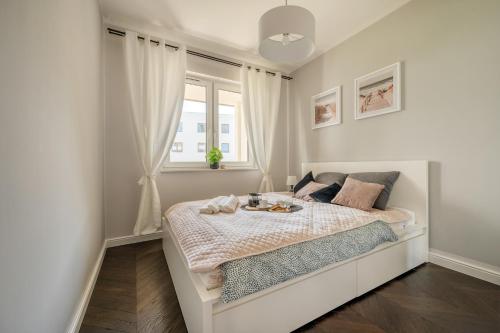 a white bedroom with a bed with a window at Łódź Retreat Apartments - Terrace, Garden & Parking - by Rentujemy in Łódź