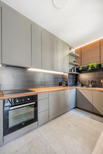 a kitchen with stainless steel appliances and wooden counters at Łódź Retreat Apartments - Parking, Terrace & Garden - by Rentujemy in Łódź