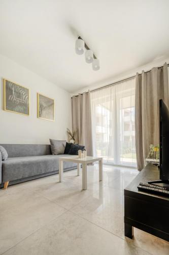 a living room with a couch and a table at Łódź Retreat Apartments - Parking, Terrace & Garden - by Rentujemy in Łódź