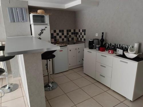eine Küche mit weißen Schränken und einem weißen Kühlschrank in der Unterkunft La maison des roses in Chadrac
