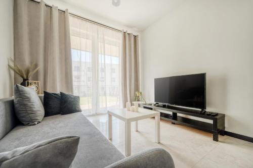 a living room with a couch and a flat screen tv at Łódź Retreat Apartments - Parking, Terrace & Garden - by Rentujemy in Łódź