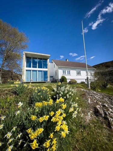 una casa blanca con flores amarillas delante en Havgaarden Villa, en Stapnes