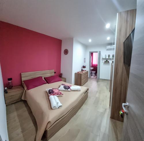 a bedroom with a large bed with a pink wall at A casa di Lina in Olbia