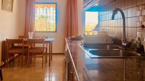 een keuken met een wastafel en een tafel met stoelen bij Click&Guest - Red Rock Apartment in Maspalomas in Playa del Inglés