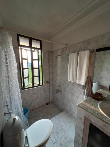 a bathroom with a toilet and a sink and a window at BelleVue Home Stay in Shillong