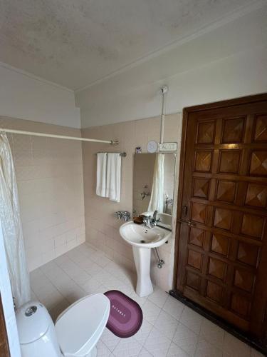 a bathroom with a sink and a toilet and a door at BelleVue Home Stay in Shillong