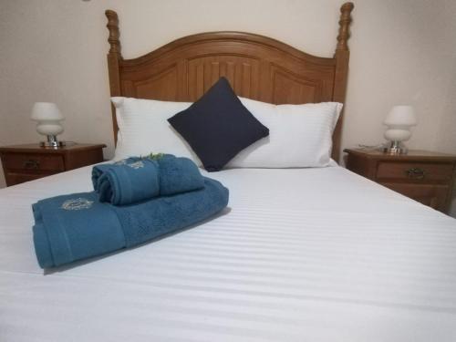 Una cama blanca grande con una toalla azul. en Residence Abrico en Mont Choisy