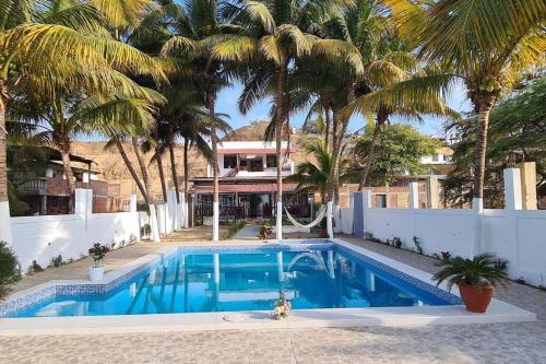 a swimming pool with palm trees in front of a house at Casa de playa Palmeras in Tumbes