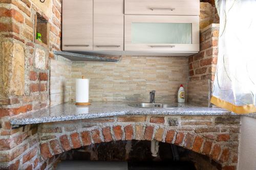 a kitchen with a sink and a brick wall at Holiday house Hana in Rovinj