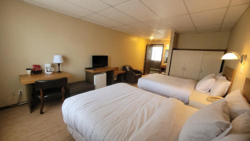 a hotel room with two beds and a desk at Hôtel Aquamer in Carleton sur Mer