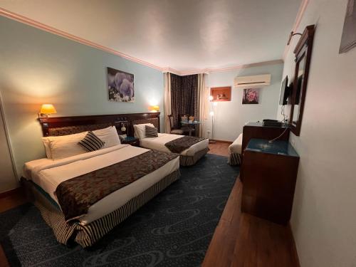 ein Hotelzimmer mit 2 Betten und einem TV in der Unterkunft Santana Hotel Cairo in Kairo