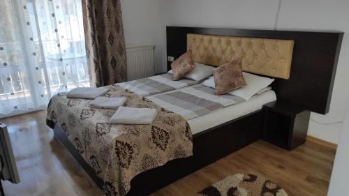 a bedroom with a large bed with a wooden floor at Vila Ariana in Baile Felix