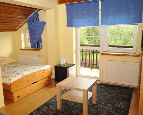 een slaapkamer met een bed en een tafel en ramen bij Ośrodek Wypoczynkowy CRYSTAL in Polańczyk
