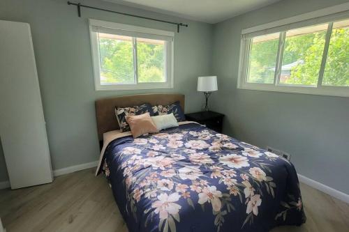 um quarto com uma cama com um edredão floral e 2 janelas em 5 bedroom w/ indoor pool/hotub em Silver Spring