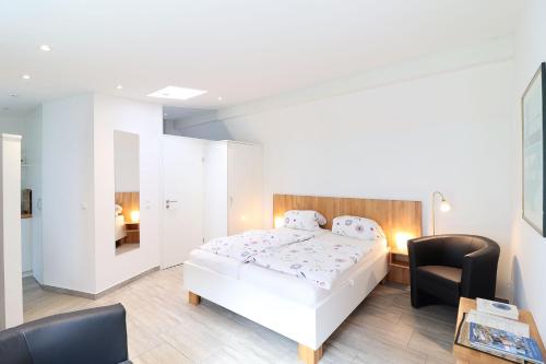 - une chambre avec un lit blanc et une chaise noire dans l'établissement Ferienwohnung- modernes Apartment in Barth am Bodden, à Barth
