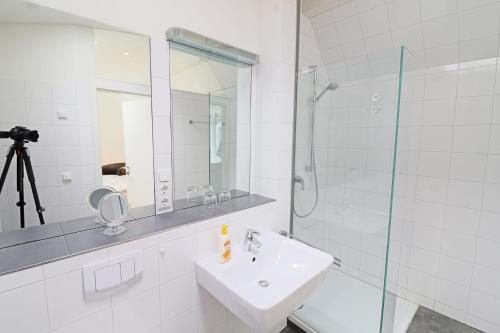 La salle de bains blanche est pourvue d'un lavabo et d'une douche. dans l'établissement Ferienwohnung- modernes Apartment in Barth am Bodden, à Barth