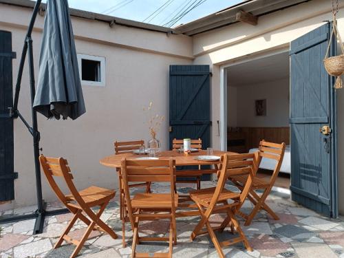 uma mesa de madeira com cadeiras e um guarda-sol num pátio em Cabanon Fabrin em Saint-Mitre-les-Remparts