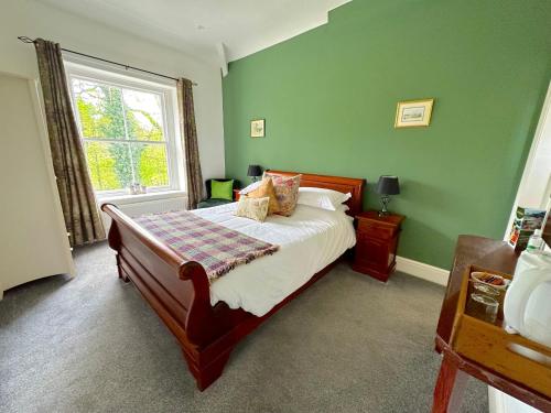 Un dormitorio con una cama con paredes verdes y una ventana en Greendale Teahouse and Rooms, en Chatburn