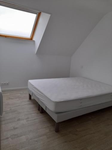 un letto bianco in una stanza con finestra di Idéalement situé pour visiter la région Pordic-Tréméloir a Pordic