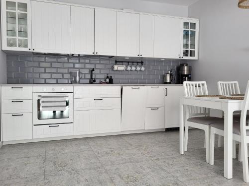 a kitchen with white cabinets and a table with chairs at Willa la Maddalena apartament in Unieście