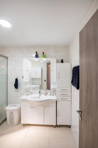 a white bathroom with a sink and a mirror at George's Paradise in Afantou