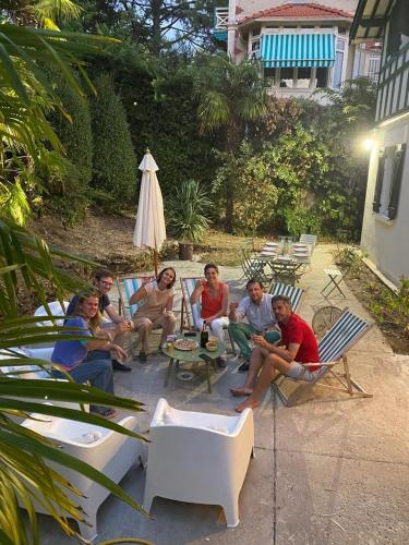 un groupe de personnes assises sur une terrasse avec des chaises dans l'établissement Grande villa - 50m plage - piscine - proche centre gare - parking, à Arcachon
