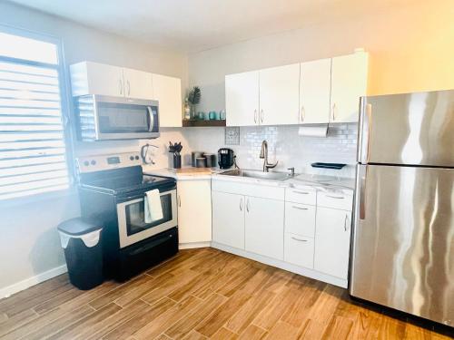 una cucina con armadi bianchi e frigorifero in acciaio inossidabile di Home for your stay a Humacao