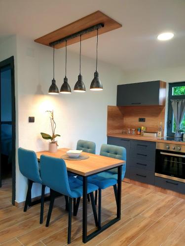 a kitchen with a wooden table and blue chairs at Apartmani Višegradski pogled in Višegrad