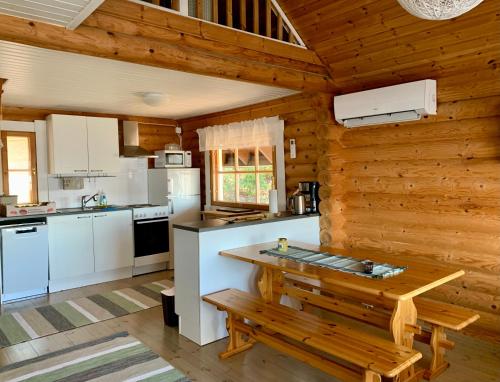 cocina con electrodomésticos blancos y pared de madera en Kesäpesä, en Artjärvi