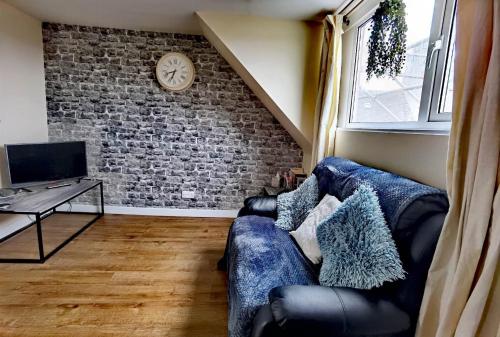 a living room with a blue couch and a brick wall at Cozy Loft In The Heart Of Kirkwall in Orkney