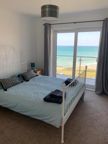 a bedroom with a bed and a large window at Two bed flat with stunning views over Fistral Bay! in Newquay