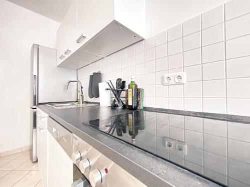 a white tiled kitchen with a counter and a sink at Gemütliche Ferienwohnung fußläufig am Markkleeberger See in Markkleeberg