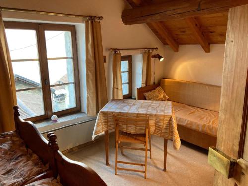 um quarto com uma mesa, uma cama e janelas em Idyllisches Rustico im verkehrsfreien Dorfkern zur Alleinbenützung em Vira