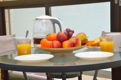 una mesa con un bol de fruta y vasos de zumo de naranja en CALO BEACH, en Costa del Silencio
