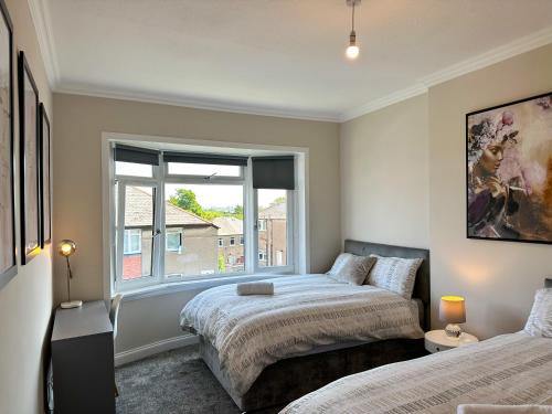 a bedroom with two beds and a window at 4 Bedrooms Homely House - Sleeps 6 Comfortably with 6 Double Beds,Glasgow, Free Street Parking, Business Travellers, Contractors, & Holiday-Goers, Near All Major Transport Links in Glasgow & City Centre, Perfect for Common Wealth Games 2026 in Glasgow