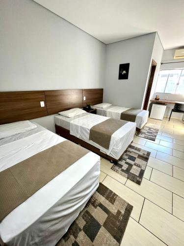 a hotel room with three beds in a room at Nantes Executive Hotel in Pitanga