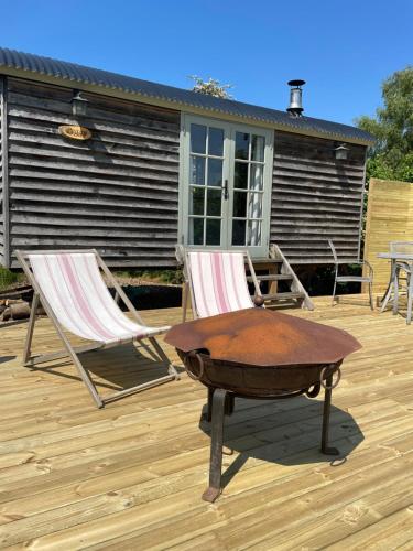 two chairs and a table on a deck at The Hut - A Shepherd's Hut on our family farm in Warwickshire in Evesham