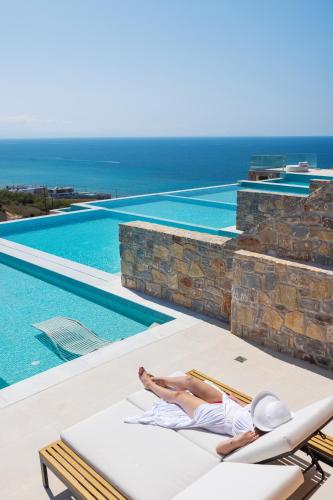 a woman laying on a chaise lounge next to a swimming pool at Dedalos Touch Boutique Hotel in Skaleta