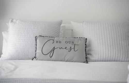 un lit blanc avec un oreiller avec les mots « soyez notre invité » dans l'établissement Super Stylish Flat Very Close to Freeman Hospital!, à High Heaton
