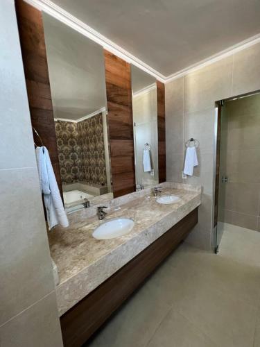 a bathroom with two sinks and a large mirror at Nantes Executive Hotel in Pitanga