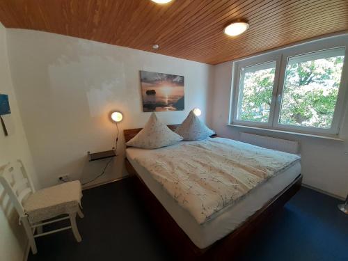 a bedroom with a bed and a chair and two windows at Ferienwohnung im Zentrum in Bad Schwartau