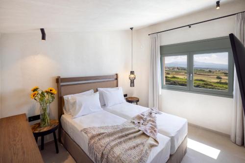 a bedroom with a bed and a large window at Dedalos Touch Boutique Hotel in Skaleta