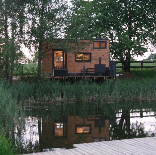 una pequeña casa en el borde de un cuerpo de agua en TinyHouse am Naturteich - Nähe Sächsische Schweiz, Dresden, en Großharthau