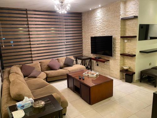 ein Wohnzimmer mit einem Sofa und einem TV in der Unterkunft Superb 2 Bed in middle of Amman in Amman